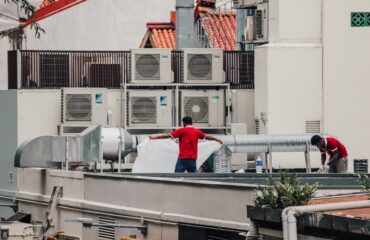 Air conditioning technicians servicing an outdoor unit on a rooftop