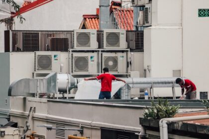 Air conditioning technicians servicing an outdoor unit on a rooftop